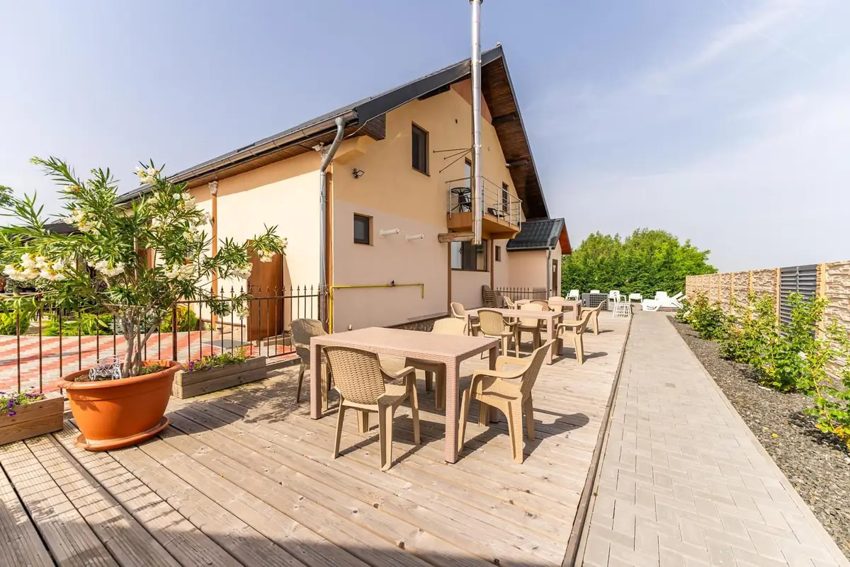 Curtea pensiunii cu oleandru înflorit și balcon la etaj